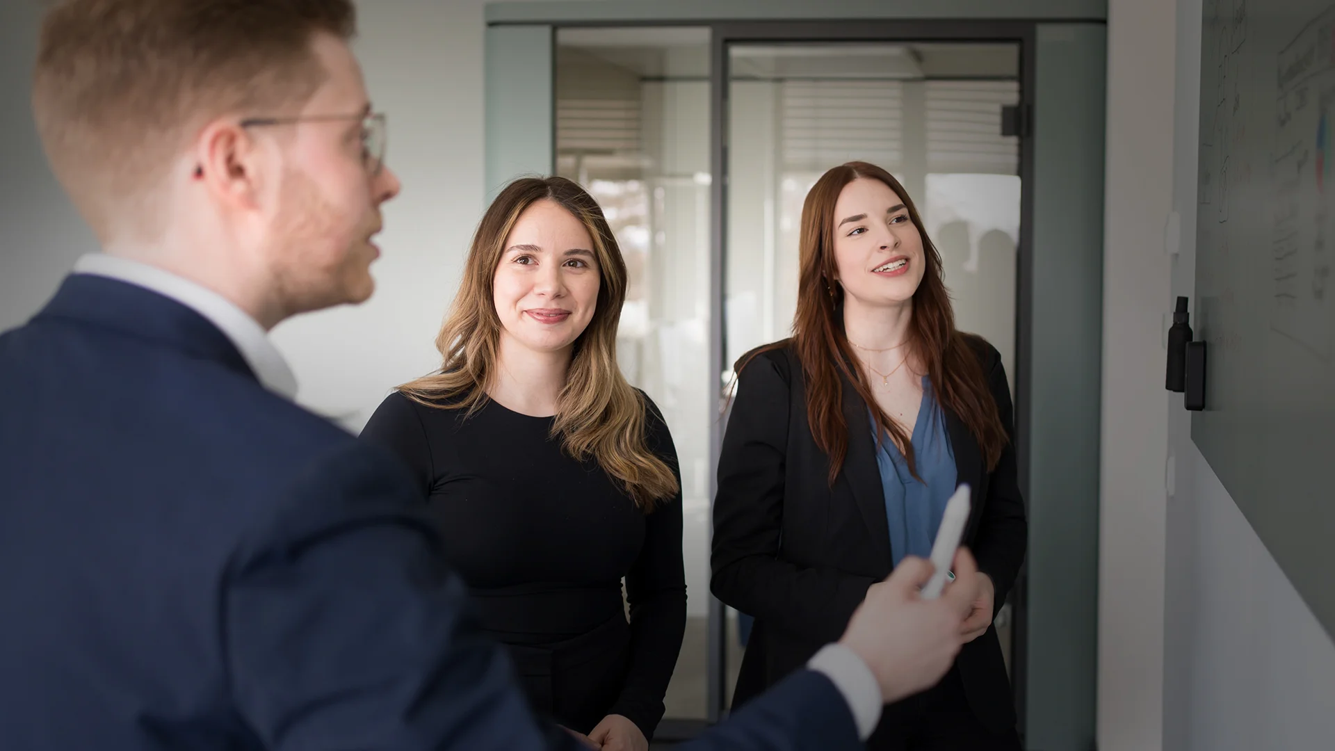 Drei Mitarbeitende von ai Consult im Gespräch an einem Whiteboard – Symbol für Teamarbeit, Nachhaltigkeit und innovative Projektentwicklung im Ingenieurwesen.